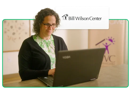 Donna che guarda un laptop, con il logo del Bill Wilson Center sullo sfondo
