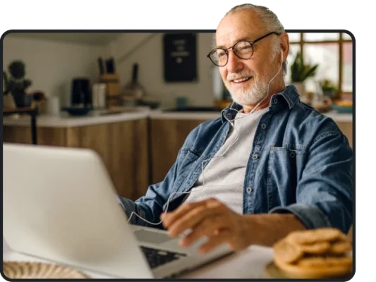 Man sitting at a table with a laptop, and headphones on