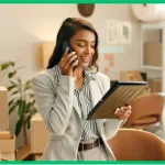 Vrouw in pak die in telefoon praat en naar een map kijkt