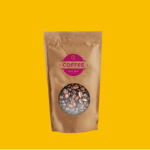 Paper bag filled with coffee beans against yellow background