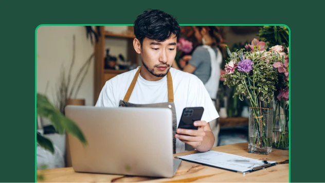 Man working in flower shop looking at phone