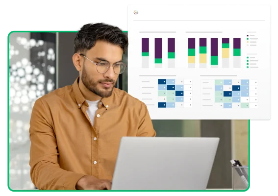 Uomo che digita al portatile accanto a schermate con grafici e diagrammi