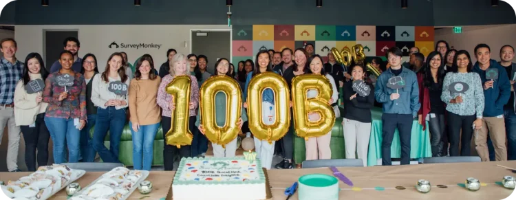 SurveyMonkey employees holding balloons that spell out 100B