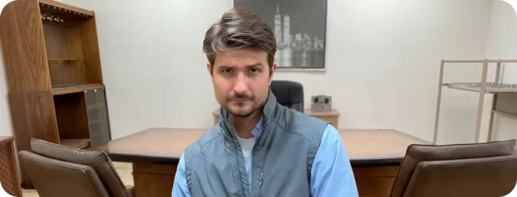 Man wearing vest sitting in front of a desk