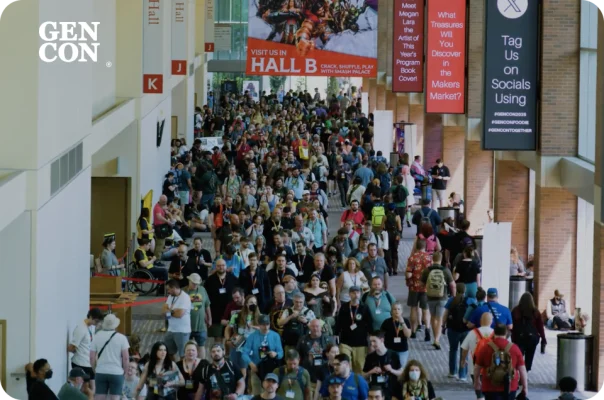 A large crowd of people walking through a convention hall at Gen Con.
