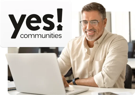 Mand ser på bærbar computer med YES Communities-logoet i baggrunden