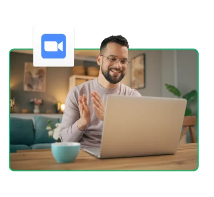 Uomo che sorride e applaude davanti allo schermo di un computer accanto al logo di Zoom