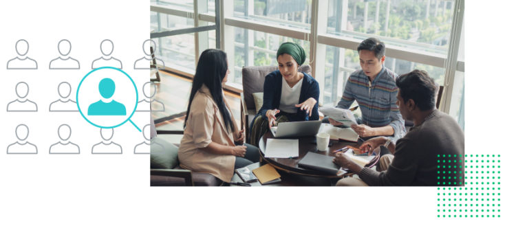 Två män och två kvinnor som sitter och pratar runt ett litet bord med datorer, surfplattor och papper på