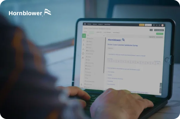 A person typing on a laptop with the Hornblower Dinner Cruise Customer Satisfaction Survey displayed on the screen.