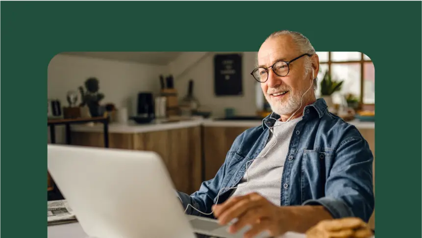 A smiling man with headphones and glasses, using a laptop.