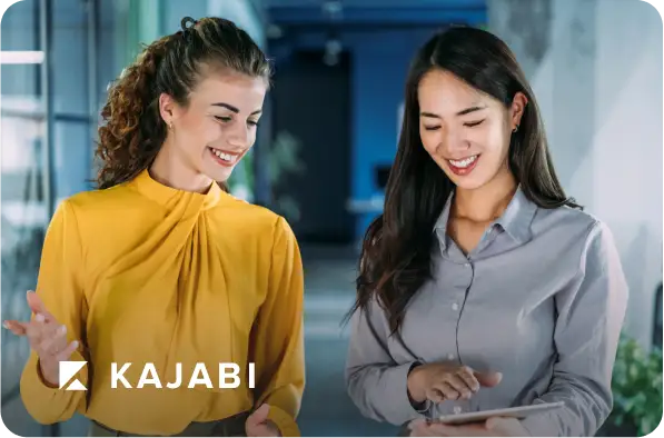 Two women looking at a tablet with Kajabi logo