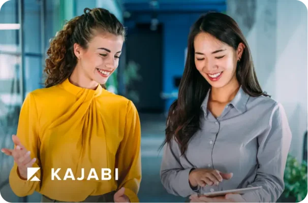 Two women smiling and wokring together, with Kajabi logo at bottom