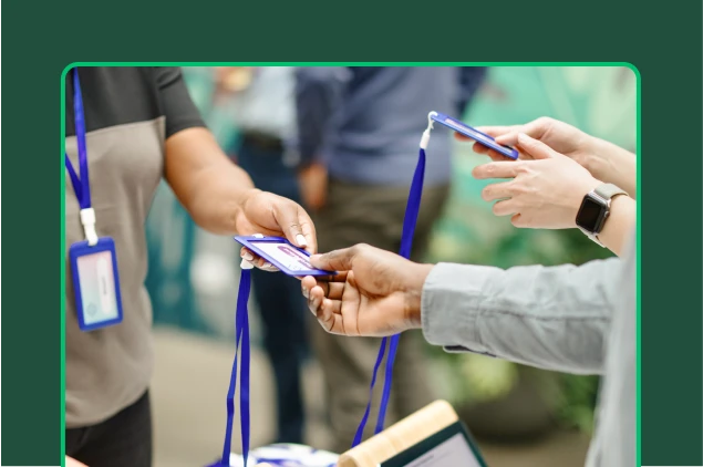 Person handing an attendance badge on a lanyard to another person at an event