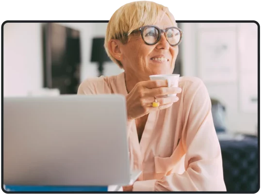 Smiling person drinking coffee with open laptop