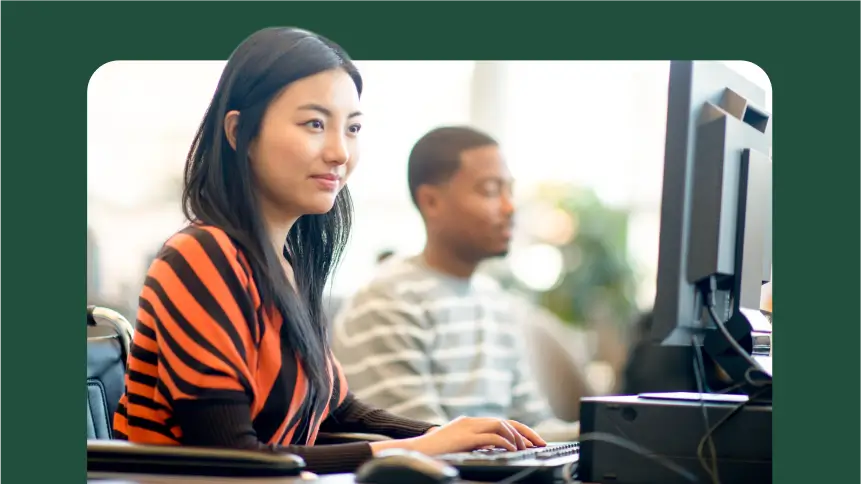 Mulher sorrindo enquanto usa o computador no escritório.