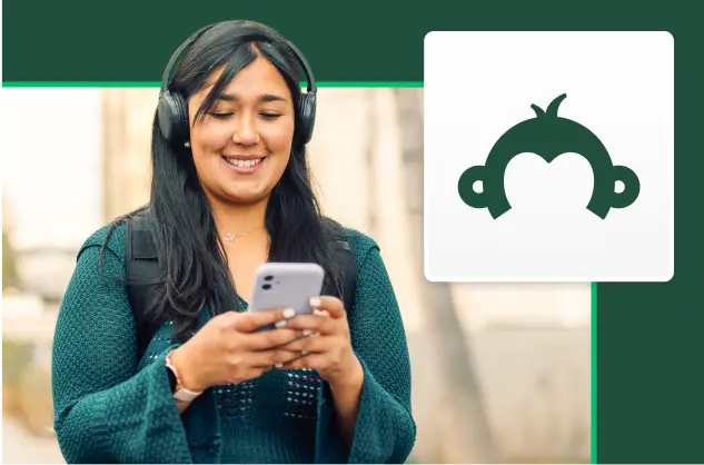 Smiling woman with headphones on and looking at phone screen, next to SurveyMonkey Goldie logo