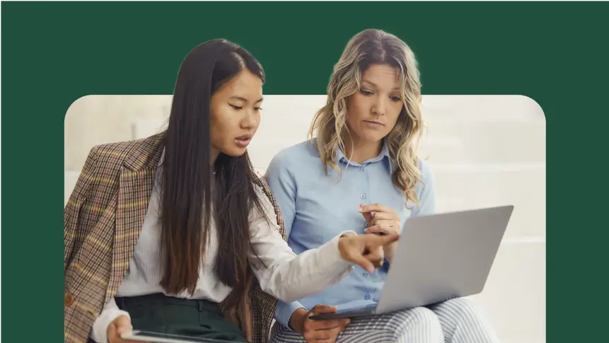 two women sitting down looking at a laptop