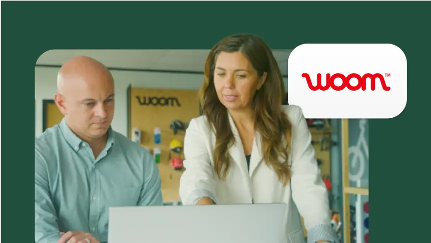 Two people, a man and a woman, are looking at a laptop screen together. The Woom company logo is shown in the corner.