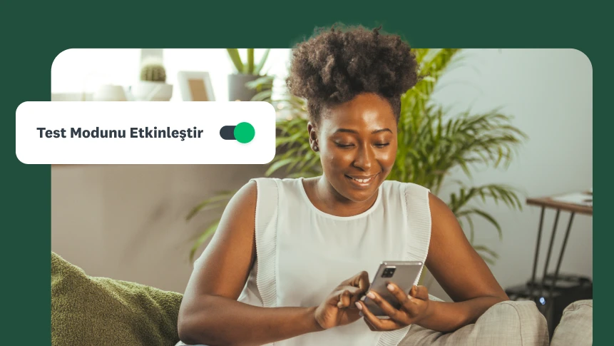 Koltukta oturarak telefonuna bakan bir kadın ve yanında &quot;Test Modunu Etkinleştir&quot; düğmesi.