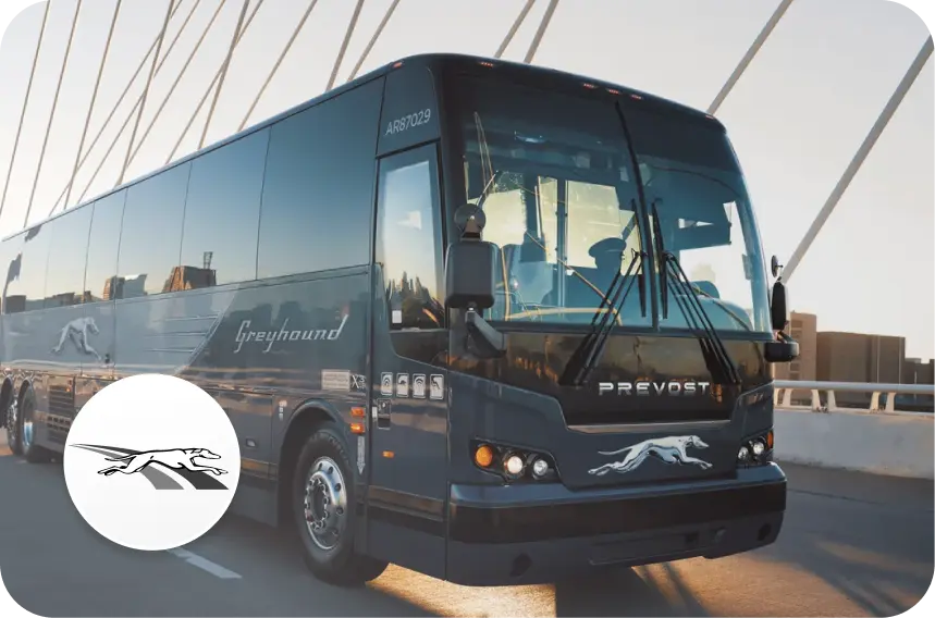 Greyhound bus driving on bridge, next to Greyhound logo