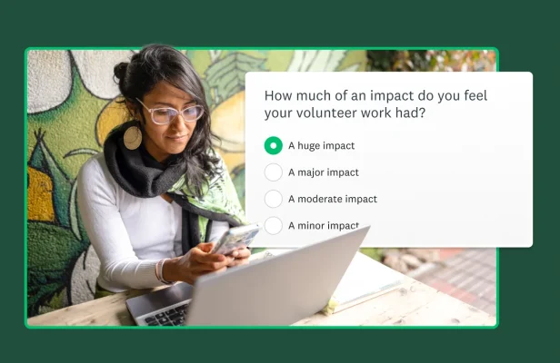 Woman looking at her computer and smartphone with an image of a non-profit survey to her right