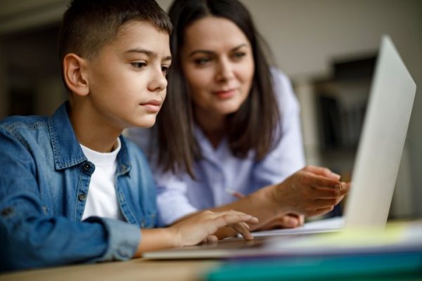 Maestra con estudiante frente a una laptop