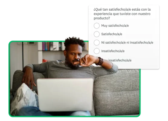 Un hombre sentado en un sillón usa una computadora con una captura de pantalla de una pregunta junto a él.