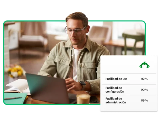 Hombre trabajando en una computadora portátil junto a una tabla que muestra las calificaciones de los usuarios para SurveyMonkey, las cuales indican que el 92 % opina que es fácil de usar, el 90 % opina que es fácil de configurar y el 89 % opina que es fácil de administrar