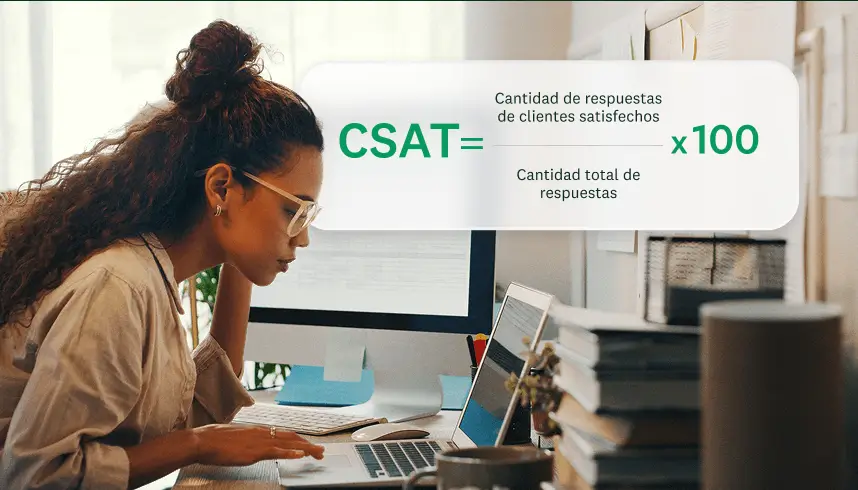 Una mujer sonriendo con una computadora portátil, junto a una superposición gráfica que muestra la fórmula para calcular la CSAT: (Cantidad de respuestas de clientes satisfechos / Cantidad total de respuestas) × 100.