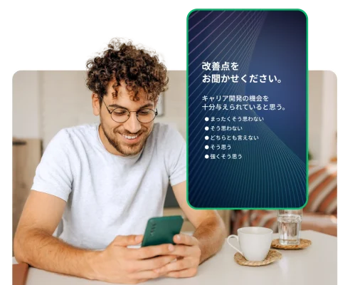 スマホ画面を見ている若い男性の隣に、改善点を聞くアンケート質問のスクリーンショット