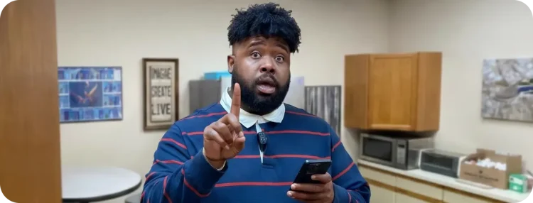 Man holding phone with finger pointed upward and a wide eyed expression