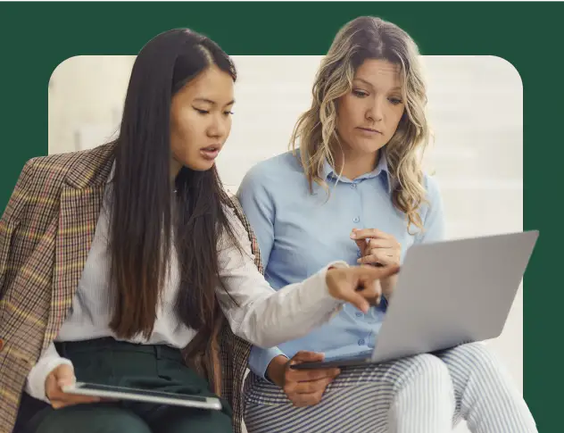 Two women looking at a laptop, with one pointing at the screen