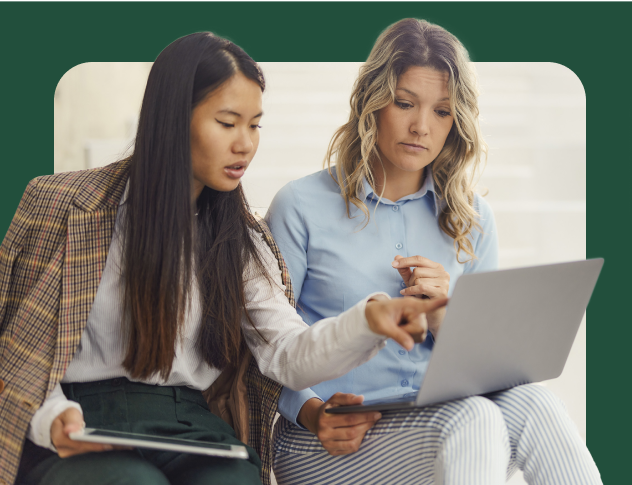 Two women looking at a laptop, with one pointing at the screen.