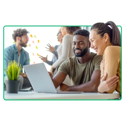Two coworkers sitting at a desk looking at a laptop