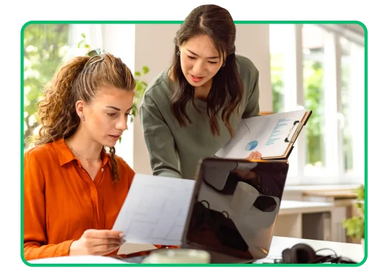 Two coworkers collaborating around a computer at a desk