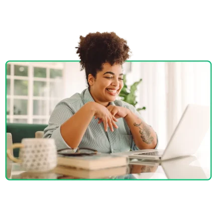 Vrouw die lachend naar haar laptop kijkt