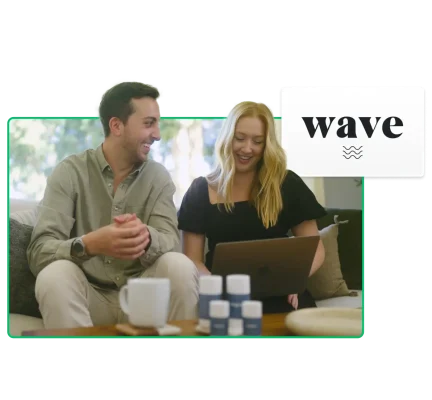 Man and woman looking at laptop with Wave logo in background and Wave products on table