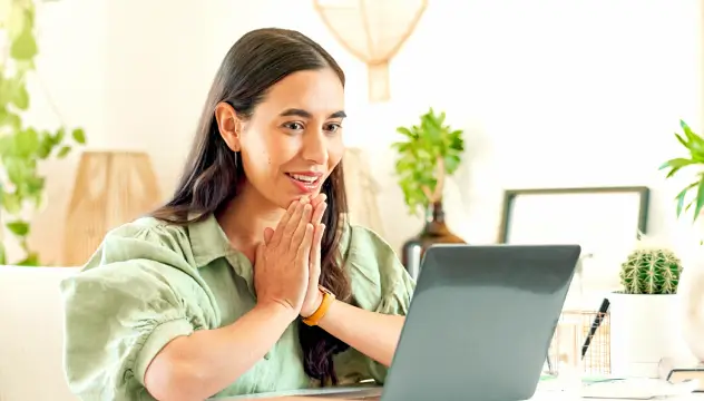 Delighted businesswoman clasping hands in excitement while looking at a laptop computer