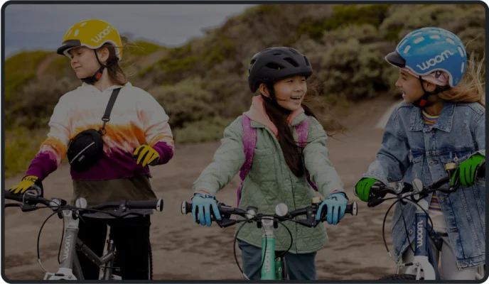 Klikattavan woom-videon esikatselukuvassa on kolme polkupyörällä ajavaa lasta