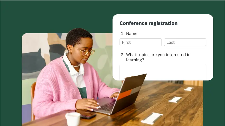 A person at a desk filling out a conference registration form on a laptop.