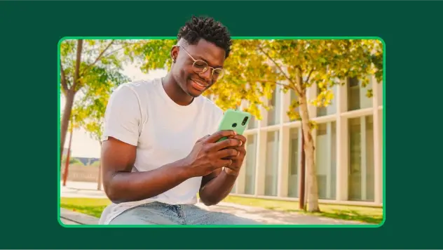 Student mit Brille und Smartphone vor einer Schule