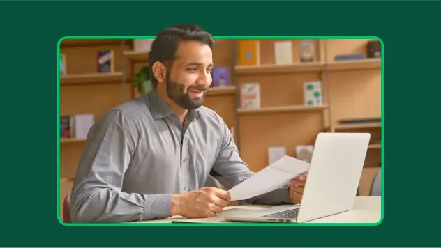 Smiling HR employee holding a piece of paper and taking a video call on laptop