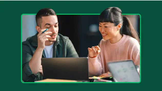 Homem e mulher lendo um artigo em um laptop e fazendo anotações em notas adesivas.