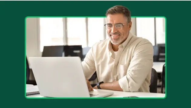 Homme souriant portant des lunettes et travaillant sur un ordinateur portable