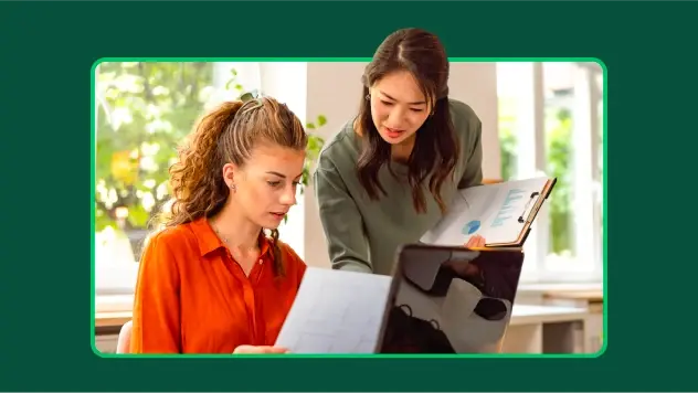 Two marketing employees, one reviewing a paper with brand strategy, and the other holding a printout of charts